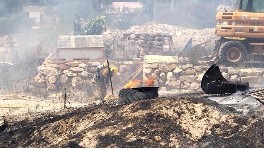 Un bombero pasa junto a un neumático en llamas