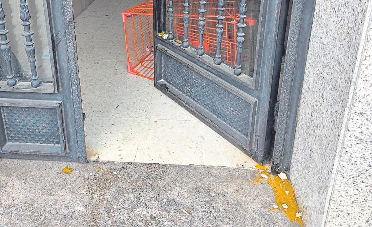 La entrada del portal, manchada con huevos rotos y ocupada por un carro de la compra.