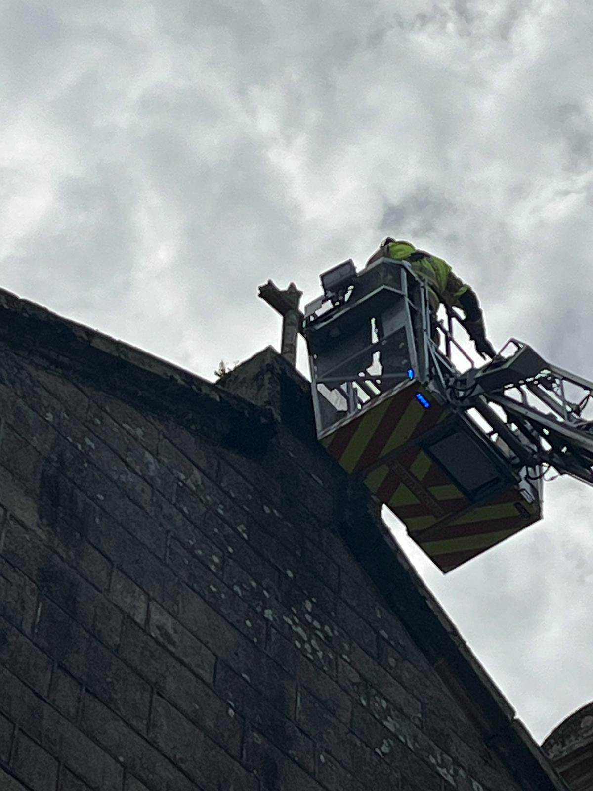 Un integrante de Emerxencias en plena retirada de la cruz que coronaba la fachada de Santa Baia.