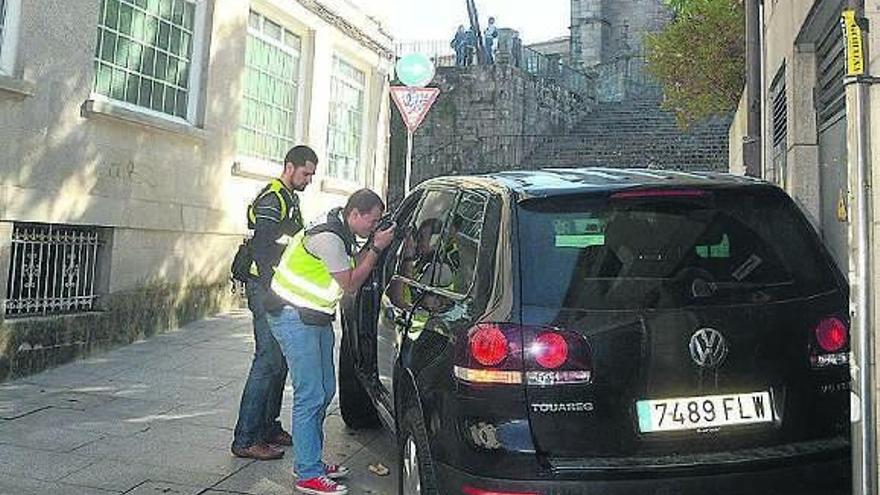 Agentes policiales inspeccionan el coche usado en la fuga. / rafa vázquez