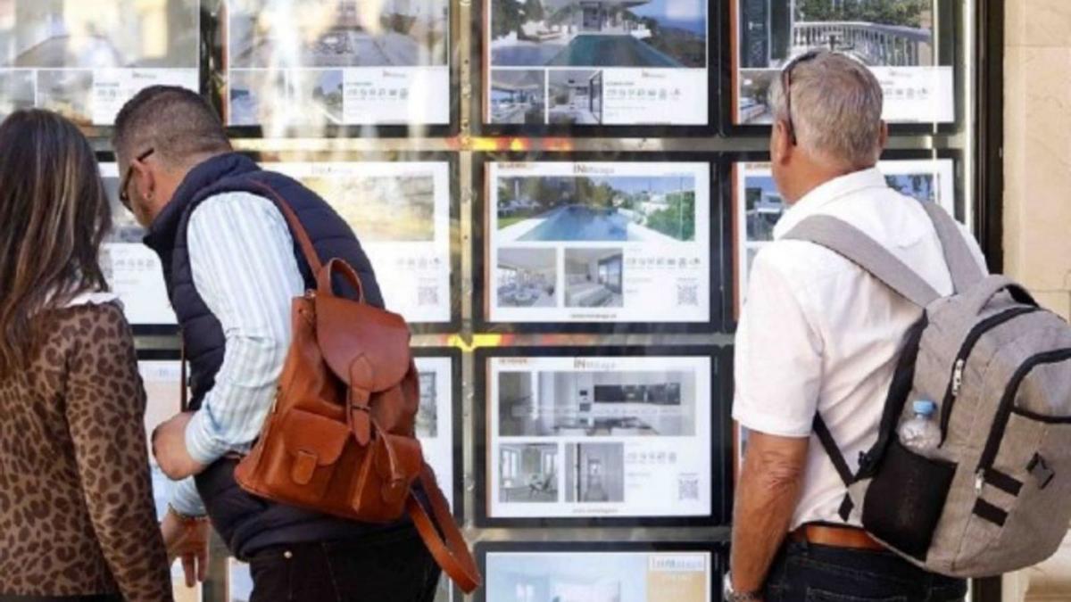 Varias personas miran los anuncios de una agencia inmobiliaria.