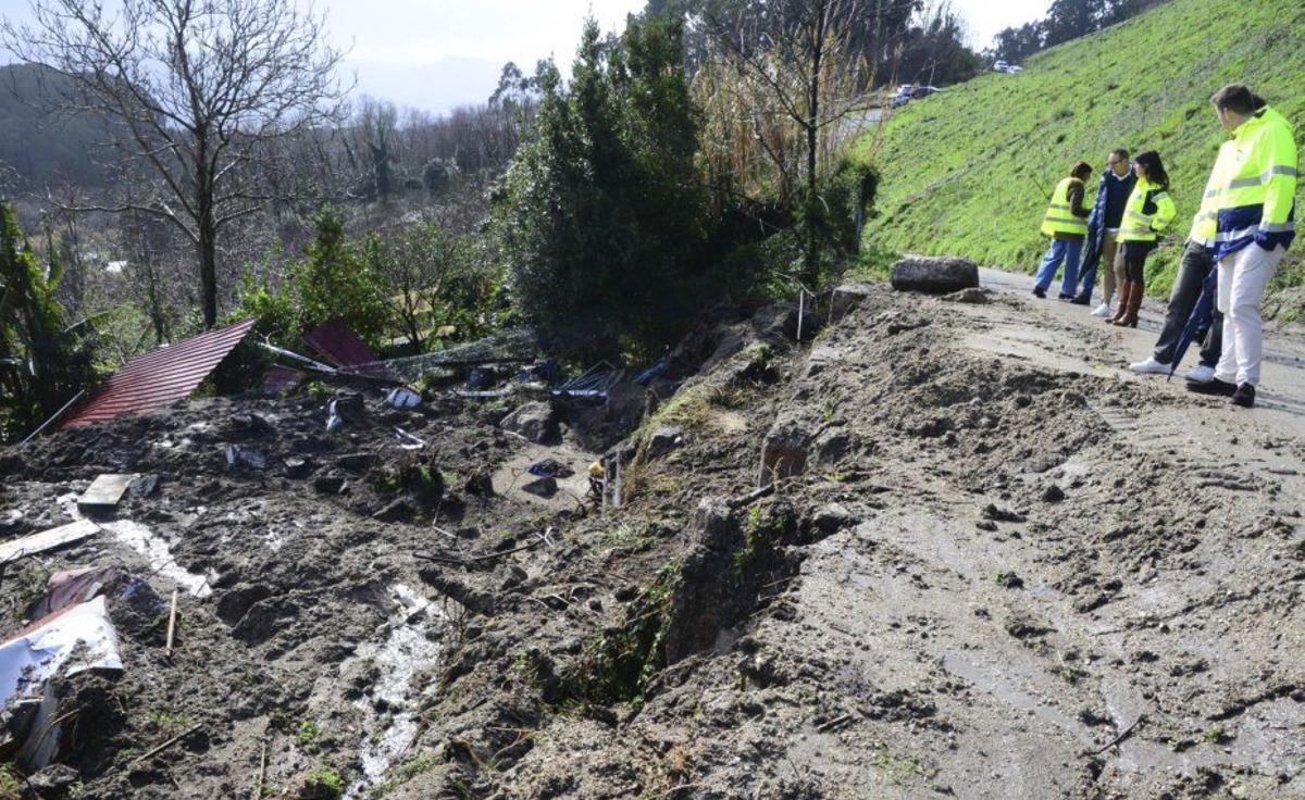 La conselleira, en el centro, ayer en el talud derrumbado sobre una casa.