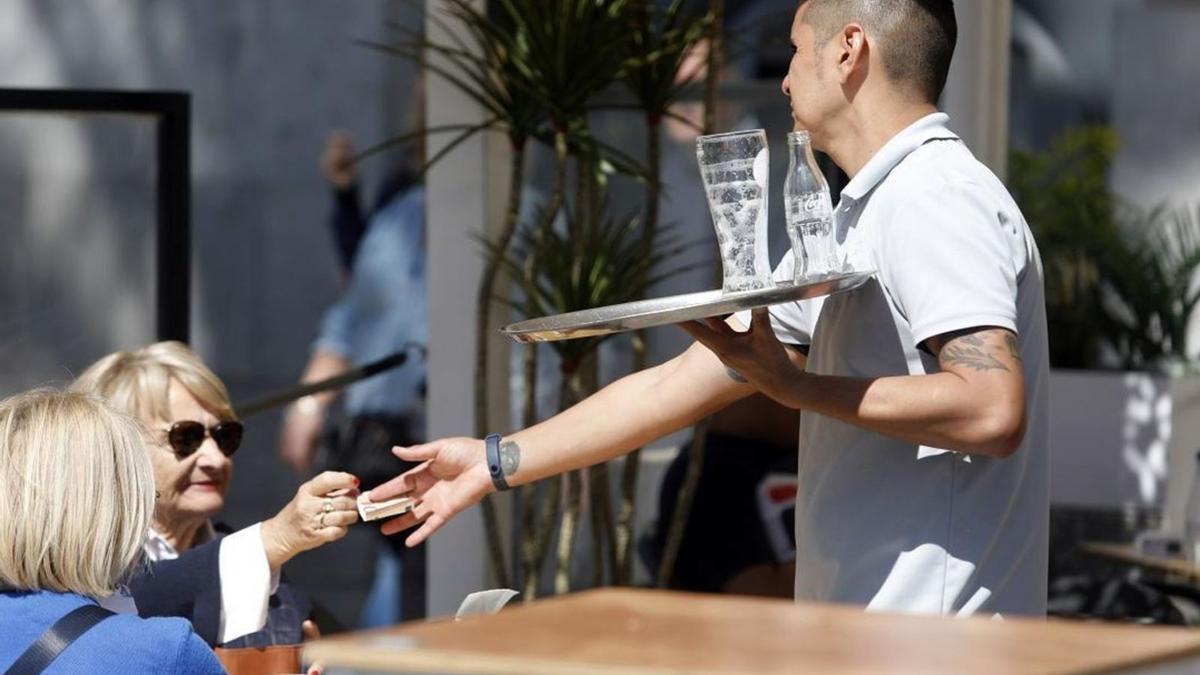 Un camarero atiende a unas clientas en un establecimiento en Málaga.  | ÁLEX ZEA