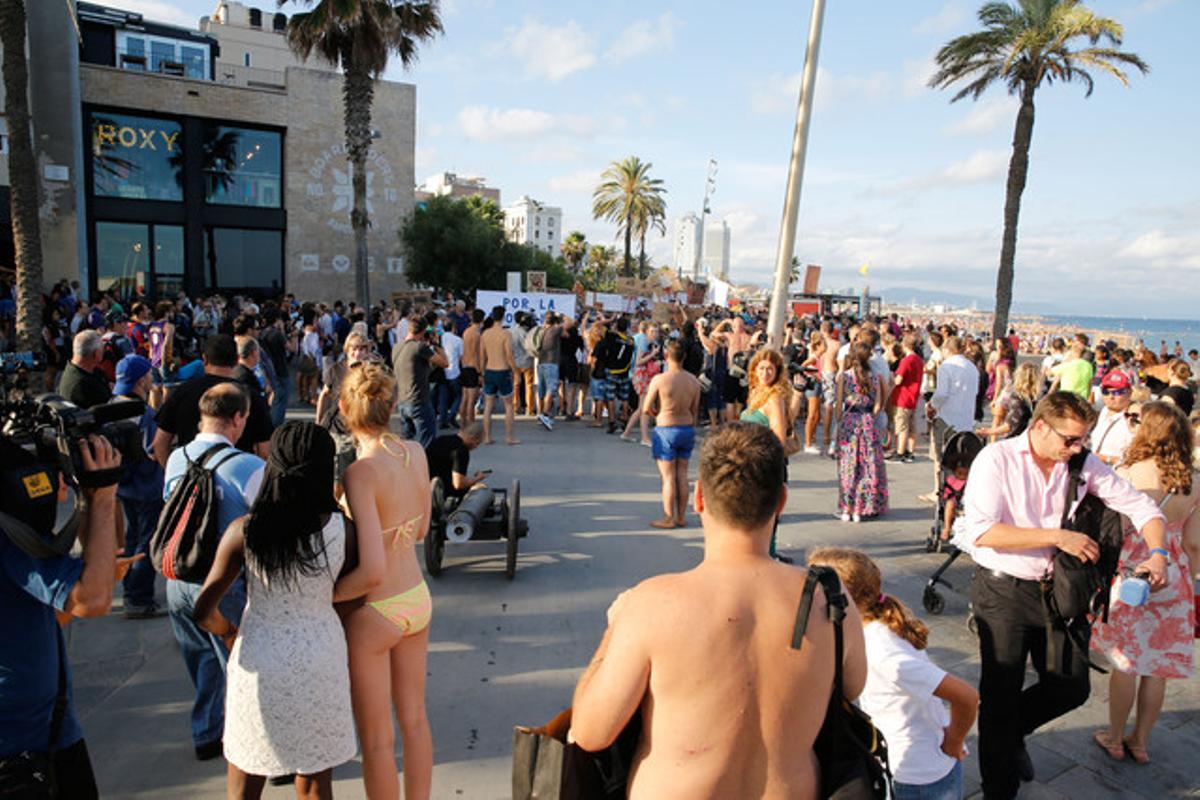 Turistas en biquini observan la protesta de los vecinos de la Barceloneta de este sábado.