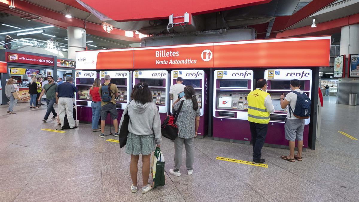 Archivo - Varias personas adquieren sus billetes en las taquillas de venta automática de la estación de tren de Atocha