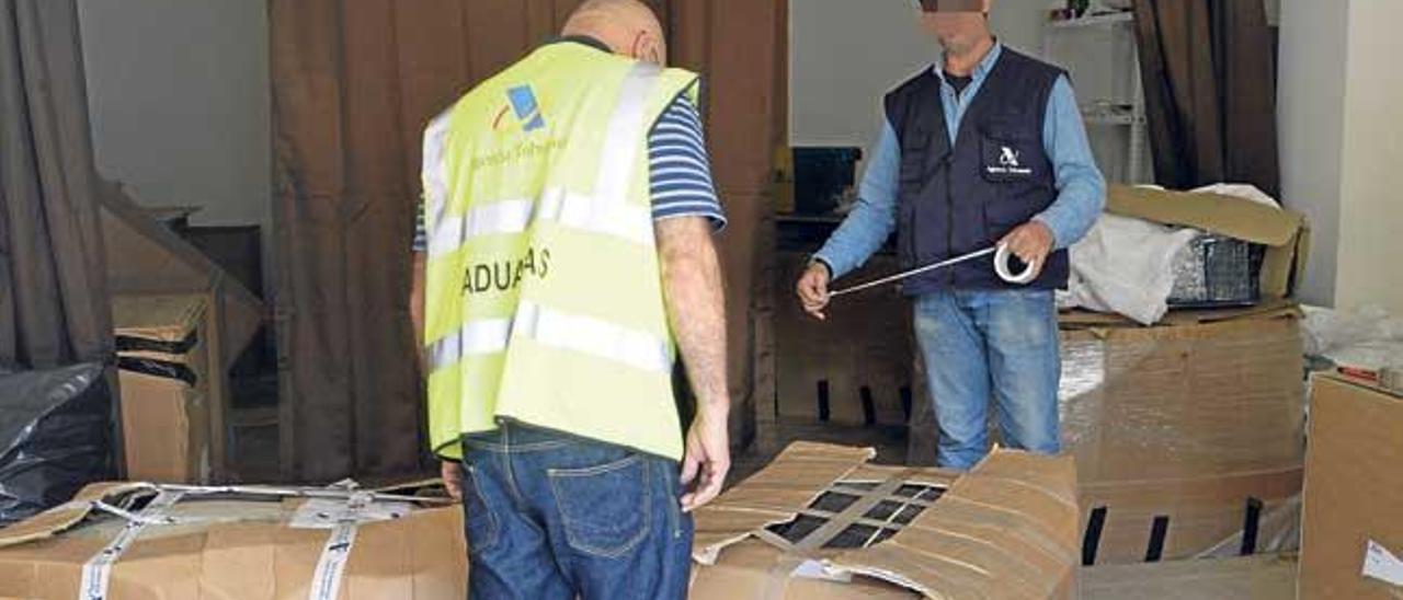 Dos agentes de Aduanas de la Agencia Tributaria precintan cajas con el material intervenido, ayer en Son Servera.