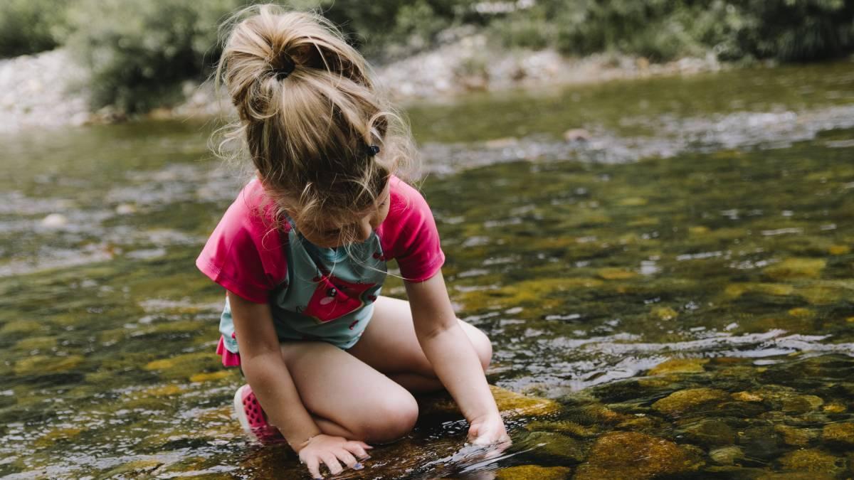 Una niña explora en un río.