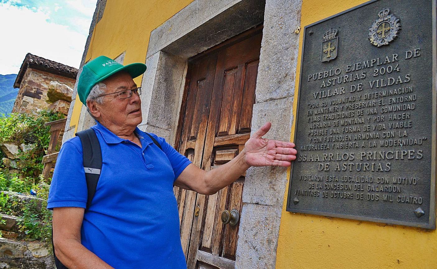 Adriano Berdasco muestra la placa conmemorativa de la entrega del premio al “Pueblo ejemplar” 2004 en la fachada del centro social, antaño las escuelas de Villar de Vildas. | Ana Paz Paredes