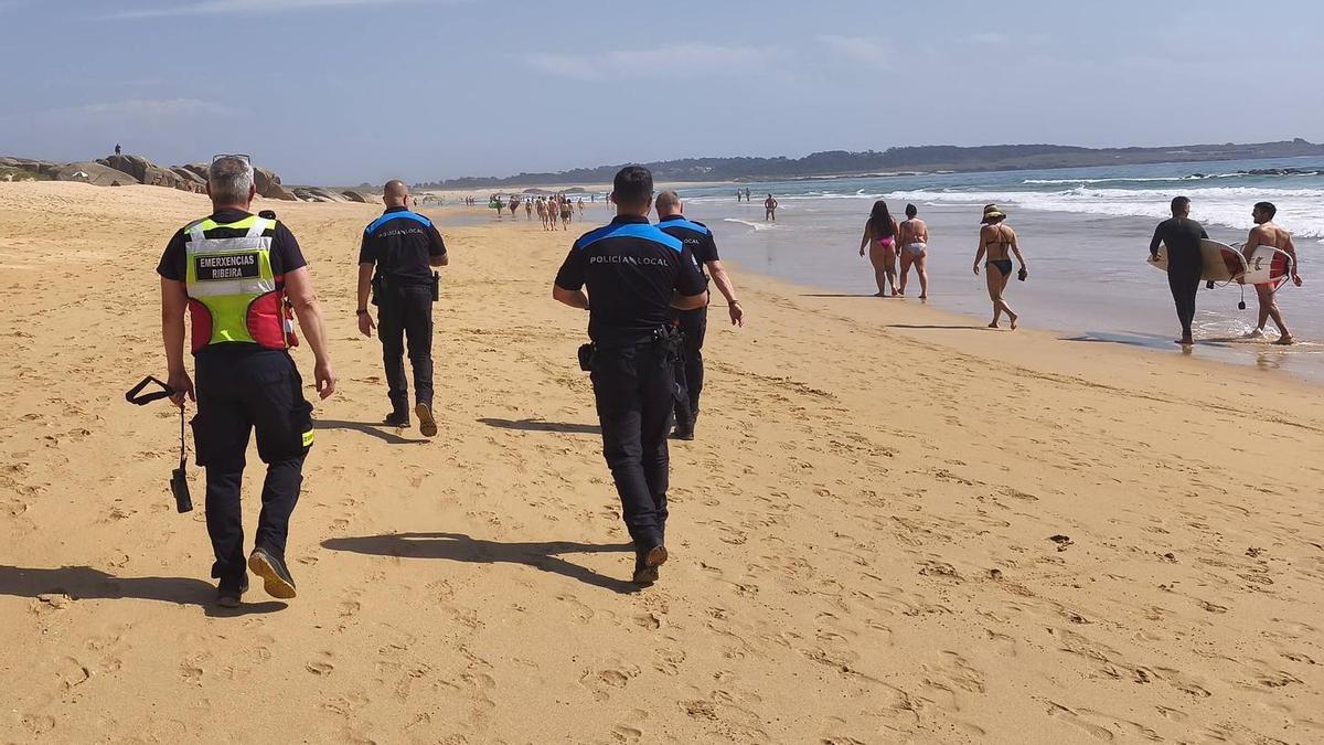Agentes de la Policía Local, personal de emergencias y surfistas, tras el rescate en la playa de O Vilar.