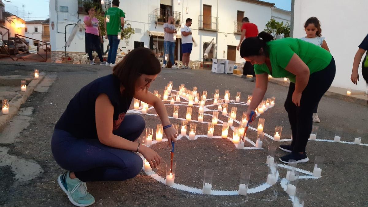 Varias vecinas encienden las velas de uno de los montajes.