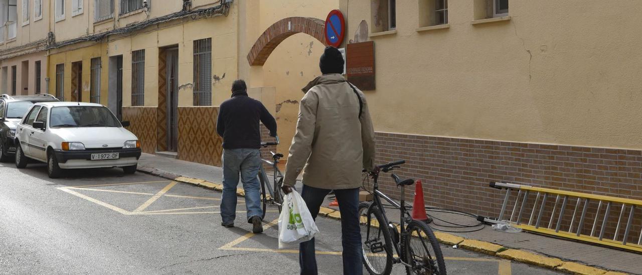 Dos hombres, con sus bicicletas, junto al comedor social de Sagunt. | DANIEL TORTAJADA