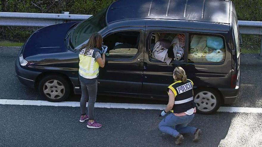 Dos agentes marcan los agujeros causados por las balas en uno de los turismos.