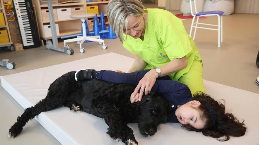 Una de las terapeutas, con una de las pacientes y un perro