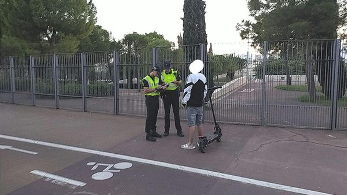 Dos policías locales, con un patinete interceptado en el carril bicil de la calle Jesús.