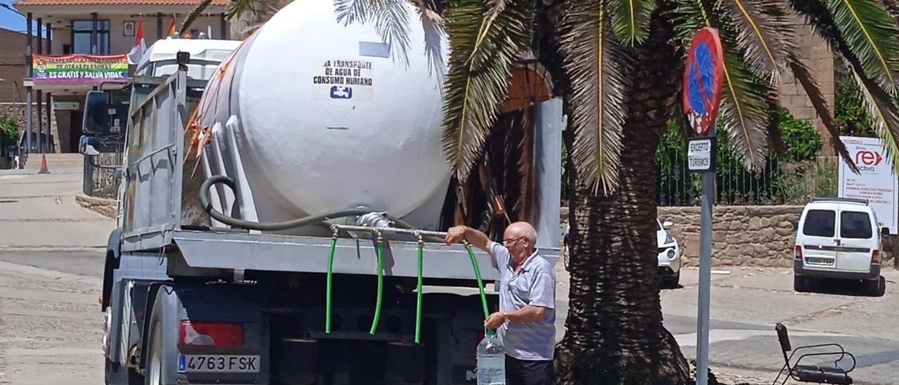 Un vecino coge agua de la cisterna que desde la pasada semana distribuye agua potable en la plaza de Peraleda.