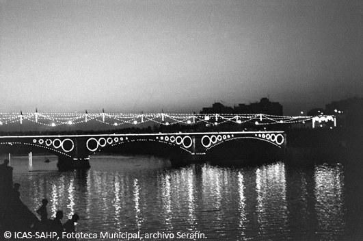 El Puente de Triana iluminado para la Velá, reflejado en el Guadalquivir, (Década de 1970)