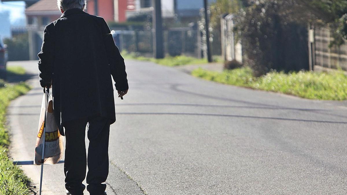 Un anciano camina solo por la carretera.