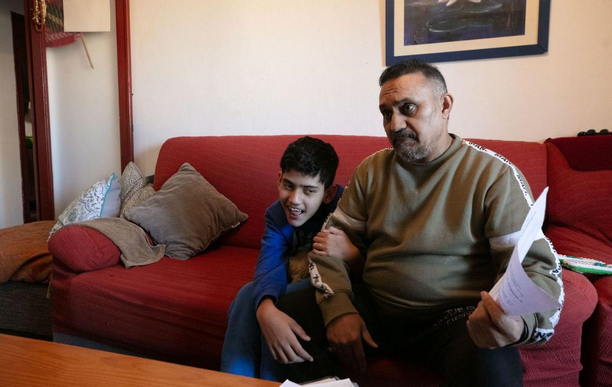 Mohammad se agarra del brazo de su padre, mientras este explica su caso. | VICENT MARÍ