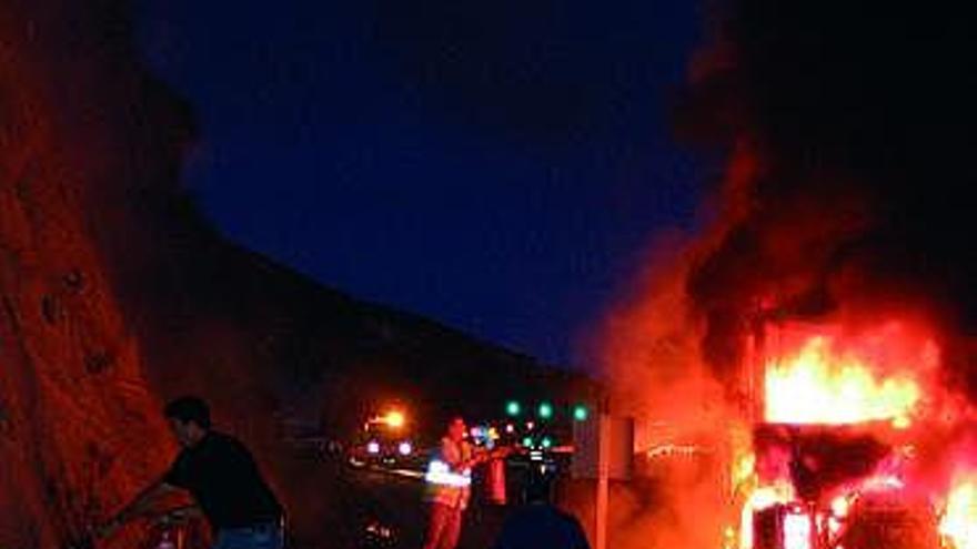 Varias personas intentan apagar las llamas del camión incendiado.