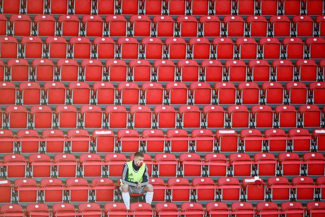 El sustituto del Bayern de Múnich con una máscara protectora mantiene la distancia social en las gradas