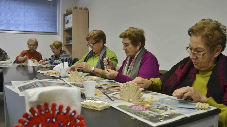 Varias mujeres elaboran un servilletero con pinzas de la ropa.