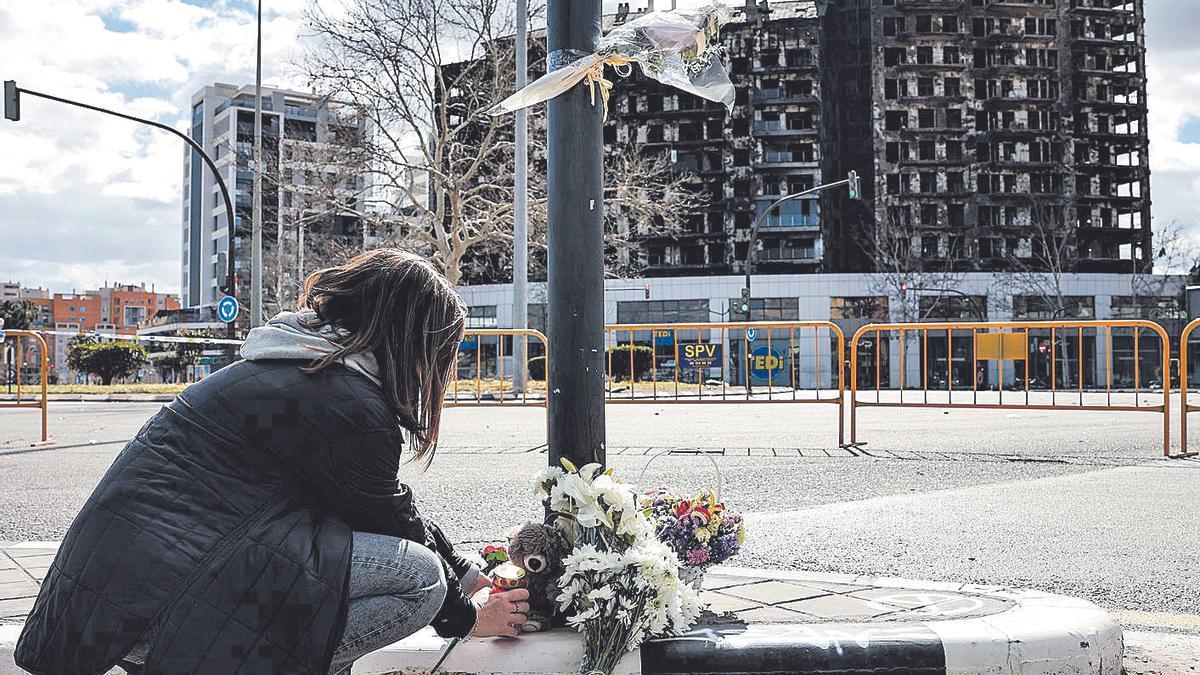 Una mujer deja un peluche frente a los edificios siniestrados.