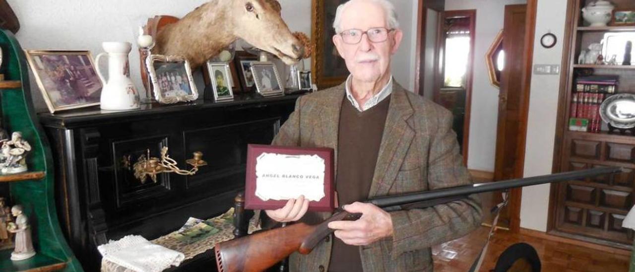 Ángel Blanco Vega, con su vieja escopeta y la placa que le entregó La Parraguesa.