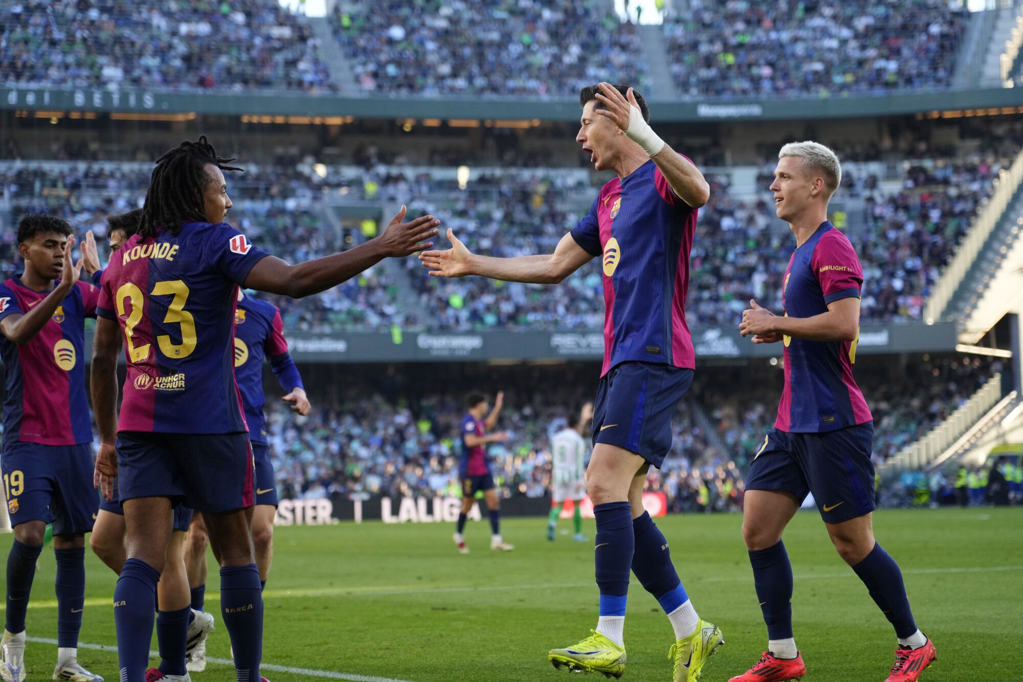 Barcelona's Robert Lewandowski, second right, celebrates after scoring his side's opening goal during a Spanish La Liga soccer match between Betis and Barcelona at the Benito Villamarin stadium in Seville, Spain, Saturday, Dec. 7, 2024. (AP Photo/Jose Breton)
