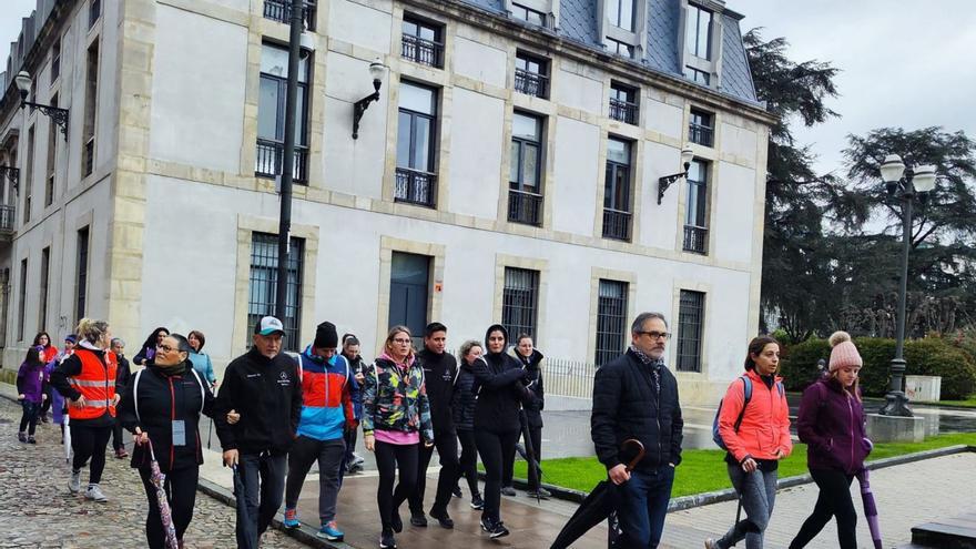 Arriba, los participantes, recién iniciada la marcha en la Pola. Sobre estas líneas, foto de familia de los asistentes ante el Ayuntamiento de Siero. | A. G.-O.
