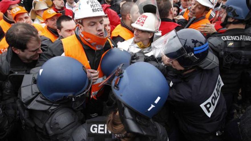 A la izquierda, la Policía francesa trata de disolver la protesta de los trabajadores de Arcelor en Florange. A la derecha, dos empleados cortando las vías del tren.
