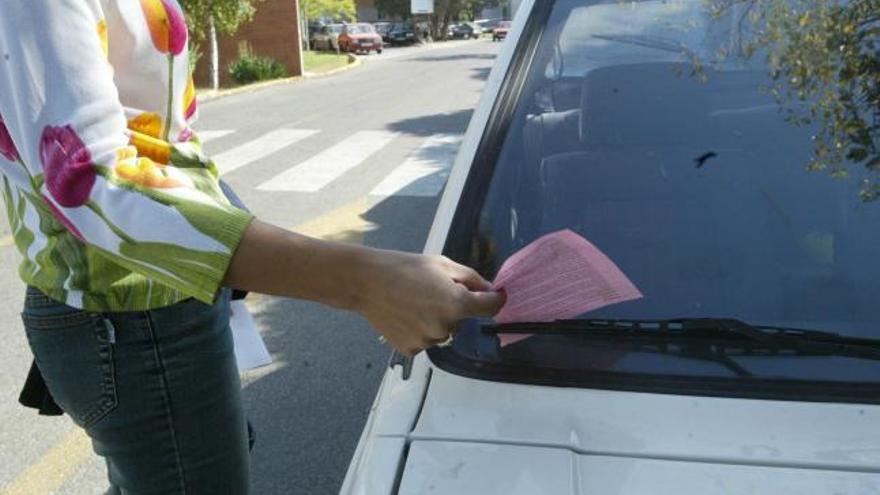 Una ciudadana recoge una multa por aparcamiento incorrecto en una de las calles de la capital donde está prohibido estacionar