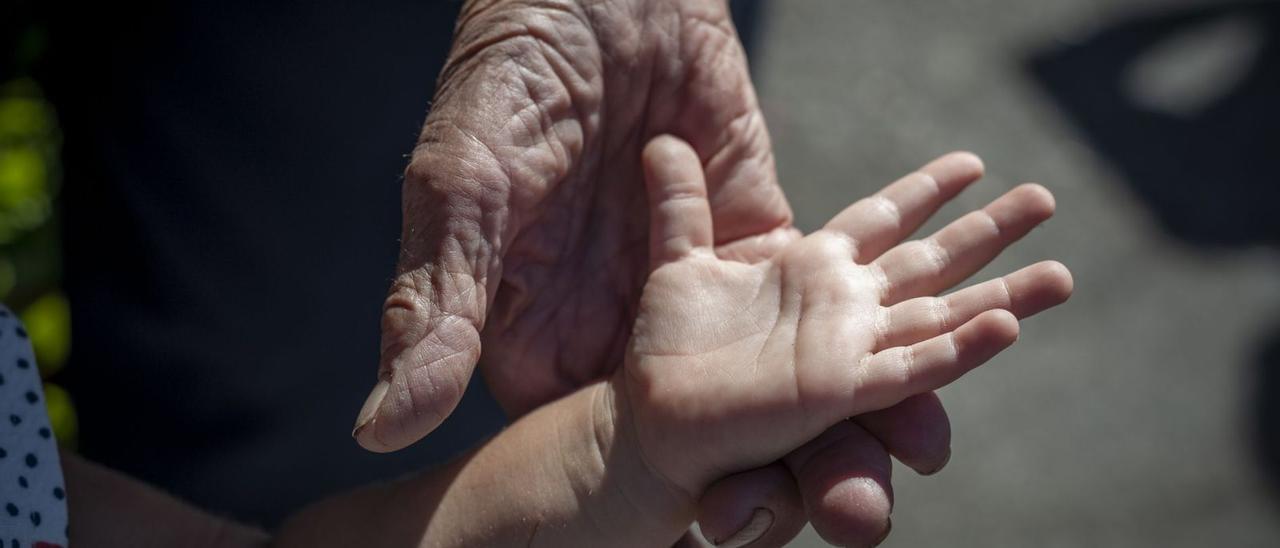 Una mujer agarra la mano de su bisnieta, en San Xoán de Río.