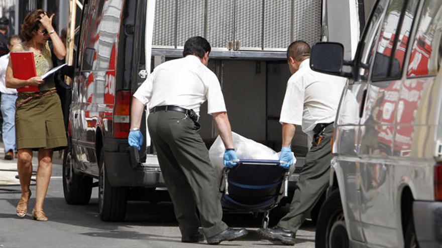 Los operarios trasladan el cadáver hasta el coche fúnebre.