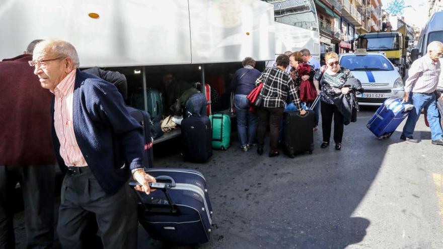 Viajeros del Imserso, cargados con maletas al bajar de uno de los autobuses que les traen a Benidorm.