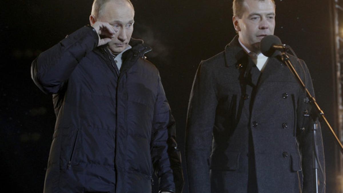 Vladimir Putin, junto al presidente Dmitri Medvedev, se seca las lágrimas, durante un acto con sus seguidores a las puertas del Kremlin, el domingo, tras las elecciones.