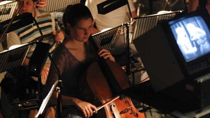 ensayo. Desde la izquierda, los músicos de «Oviedo Filarmonía» ensayan la partitura, con un monitor encima del atril del director; Marzio Conti y Vicente Domínguez se dan la mano en el foso del Campoamor, y los músicos repasan la pieza con sus partituras de «Metrópolis» traídas desde Alemania. | luisma murias