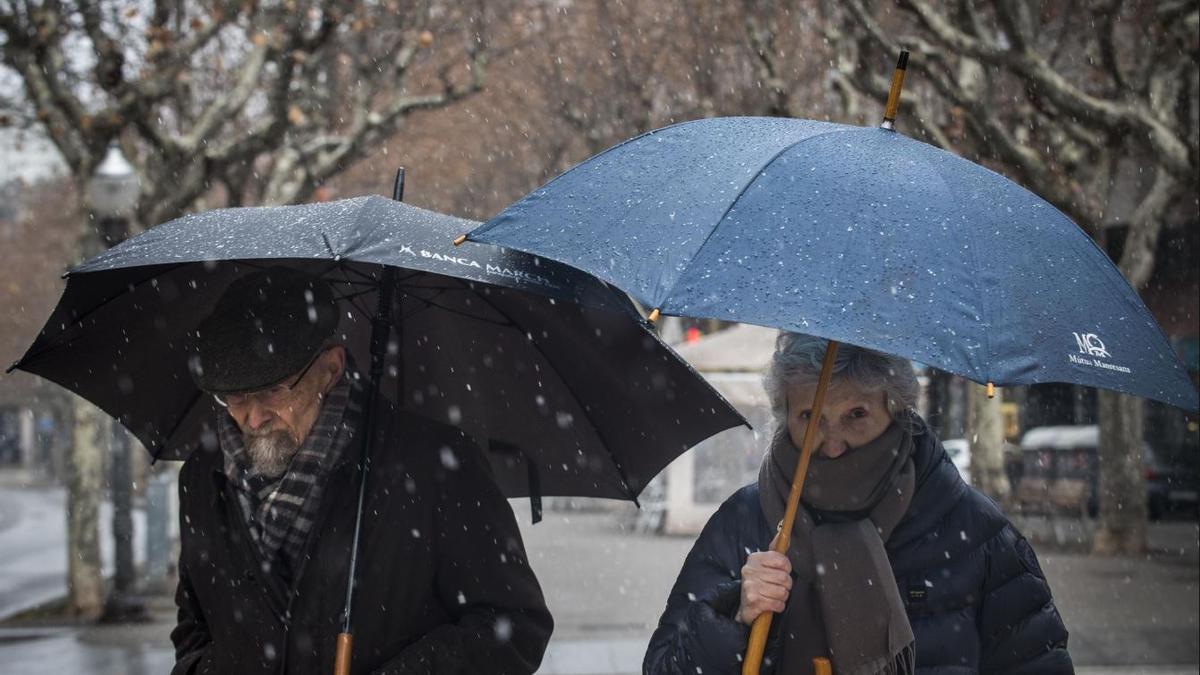 Dues persones resguardant-se de la neu, fa un any a Manresa