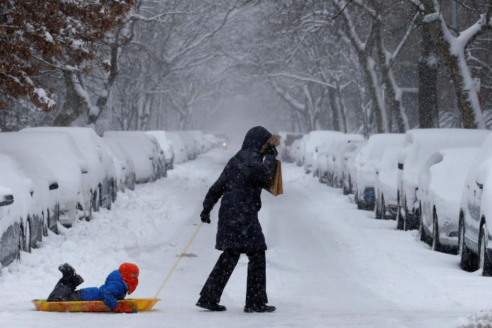 Una gran nevada ha cubierto Nueva York de nieve. En la imagen, una mujer arrastra el trineo de su hijo en Brooklyn.