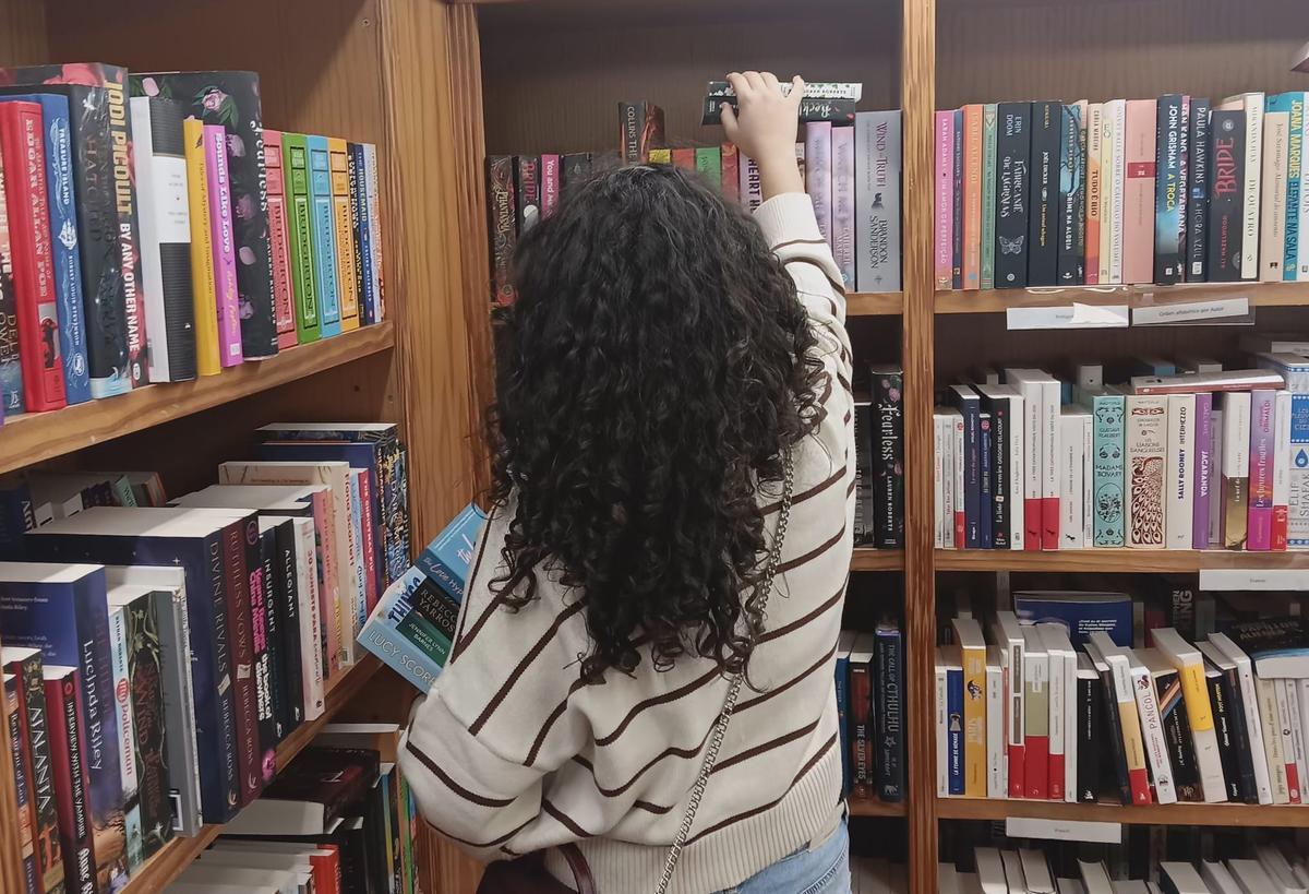 Una niña coge libros de una estantería.