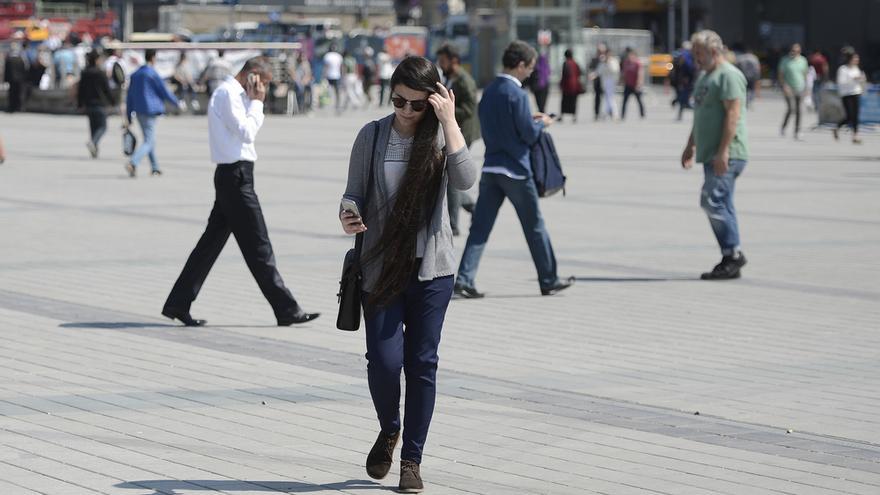 Una mujer camina mirando el móvil.