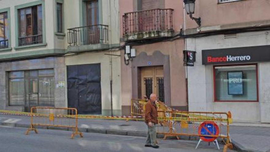 Un peatón se ve obligado a circular por la calzada por culpa del vallado dispuesto para prevenir el peligro de desprendimientos del edificio del número 12 de la calle La Vega. | mariola menéndez