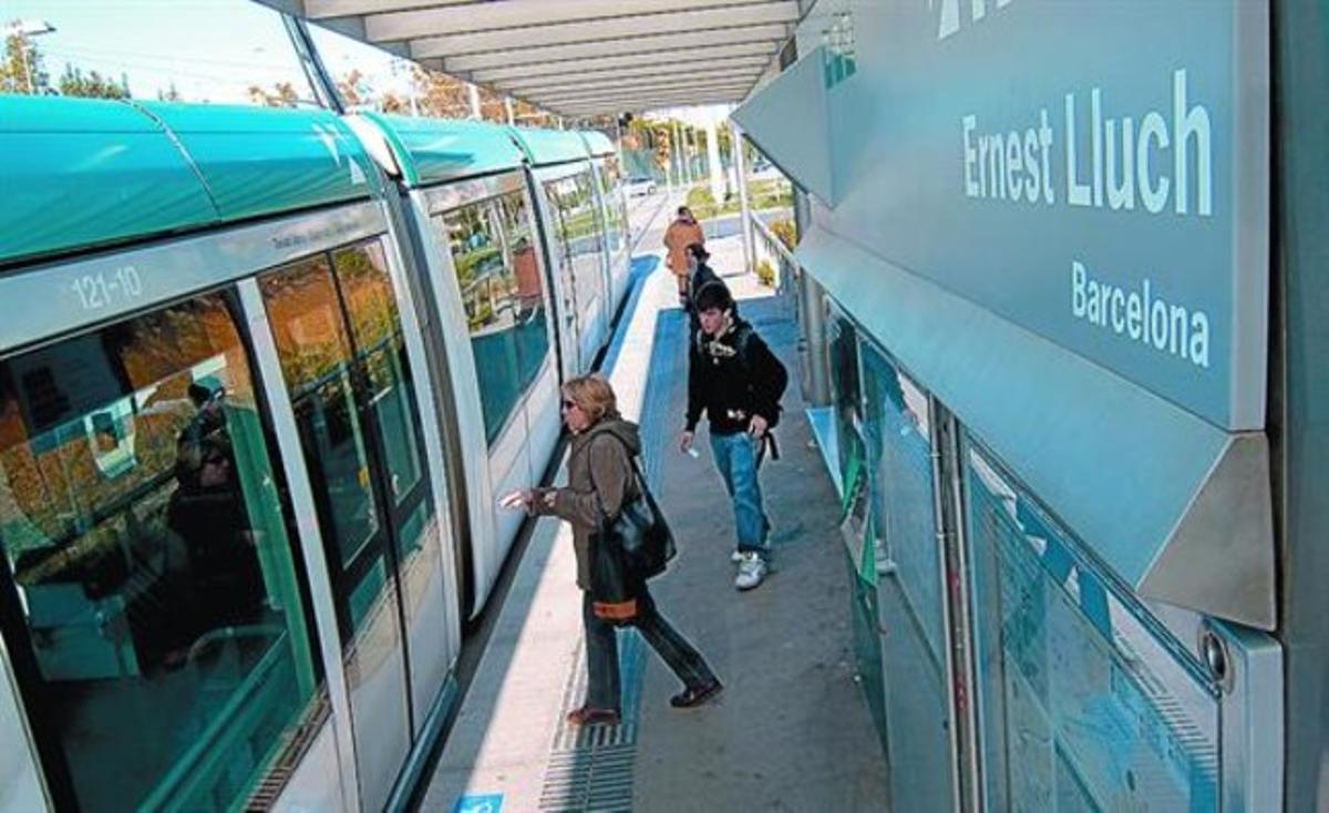 Uns passatgers pugen al Trambaix a la parada d’Ernest Lluch, entre les Corts i Collblanc.