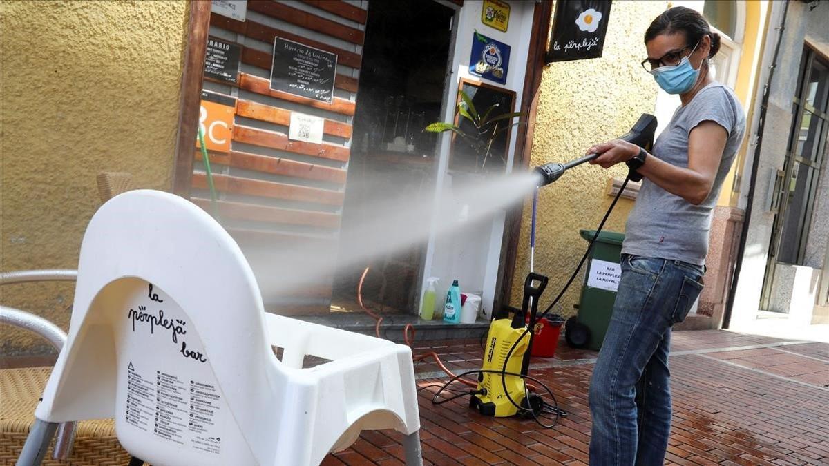 La propietaria de un bar desinfecta con agua y lejía una trona en Las Palmas.