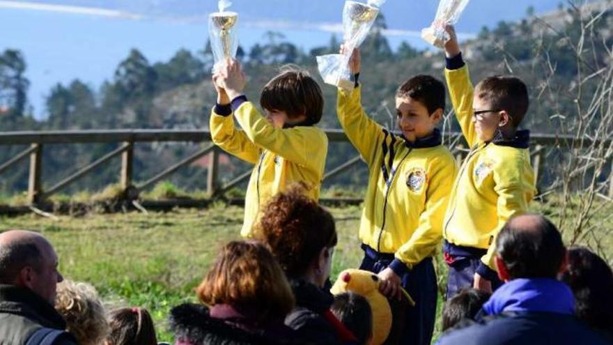 Los tres integrantes de uno de los podios levantan sus trofeos en Varalonga, con la ría de fondo. // G.N.