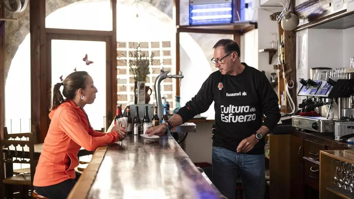 Marina Albesa (i), conversa con Pedro Silvestre (d), quien forma parte del proyecto Àmbit de reinserción sociolaboral, en el bar del Mesón de Herbers donde los integrantes del proyecto aprenden a gestionar un negocio de hosteleria.