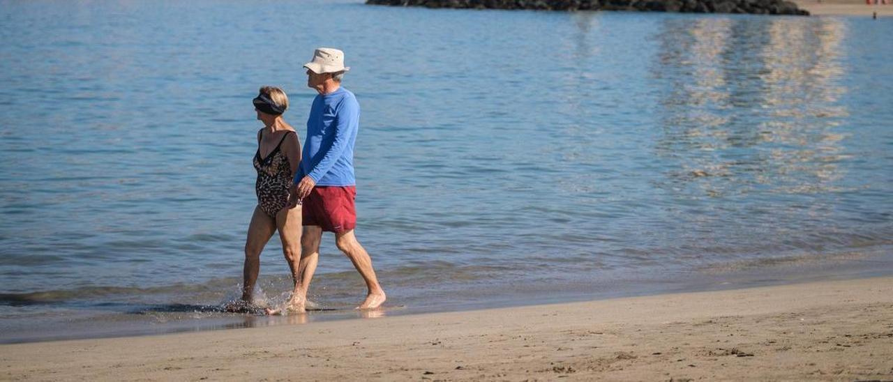 Una pareja pasea por la orilla de la playa de Los Cristianos, en Tenerife.