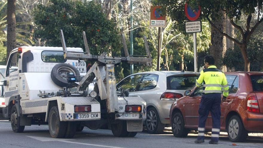 La grúa municipal y un operario trabajando frente a la Aduana.