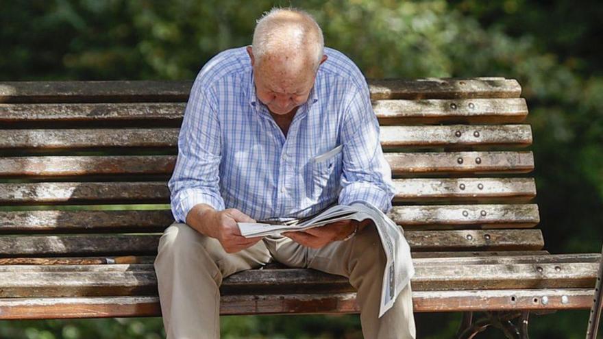 Un jubilado lee el periódico en un banco. | Luis Tejido