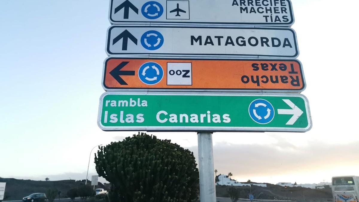 En color naranja, el rótulo colocado en posición invertida en el panel de señales instalado en Puerto del Carmen, el cual ya ha sido corregido.