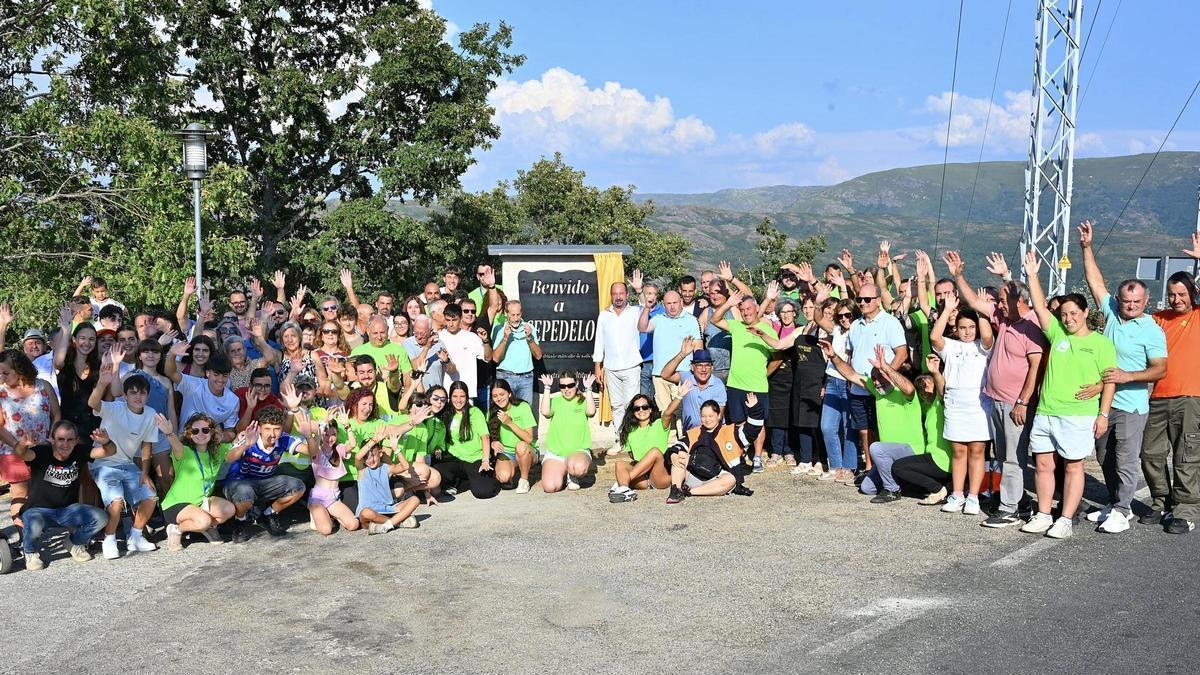 Vecinos de Cepedelo posan junto al monumento a su aldea.